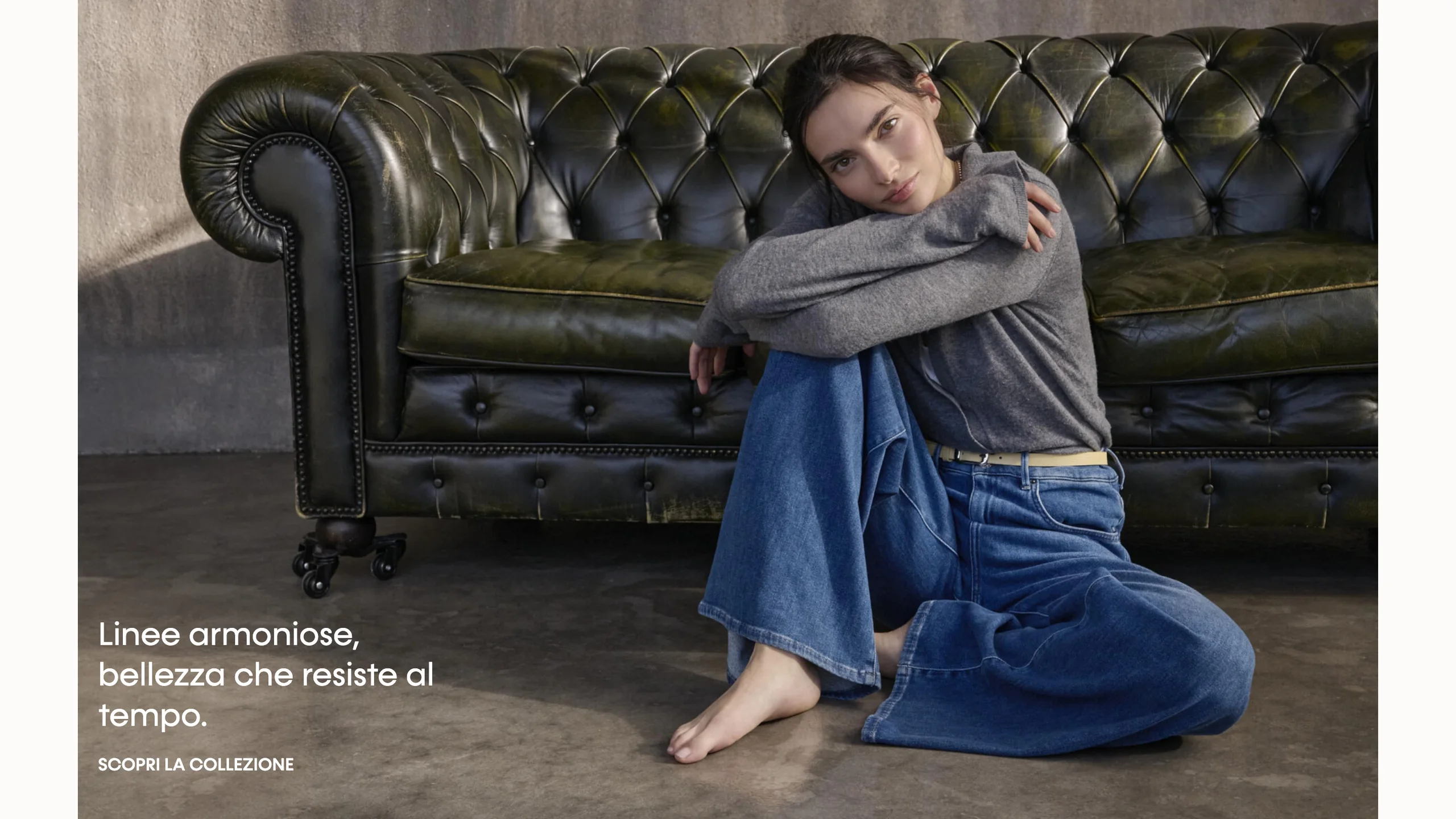 La scena editoriale della homepage: un capo indossato su un divano Chesterfield, con la frase «Linee armoniose, bellezza che resiste al tempo»